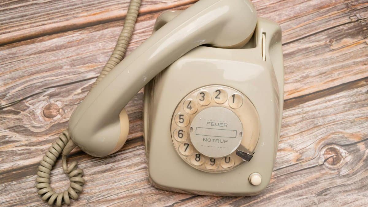 Retro rotary phone with dial on rustic wooden surface, nostalgic feel.