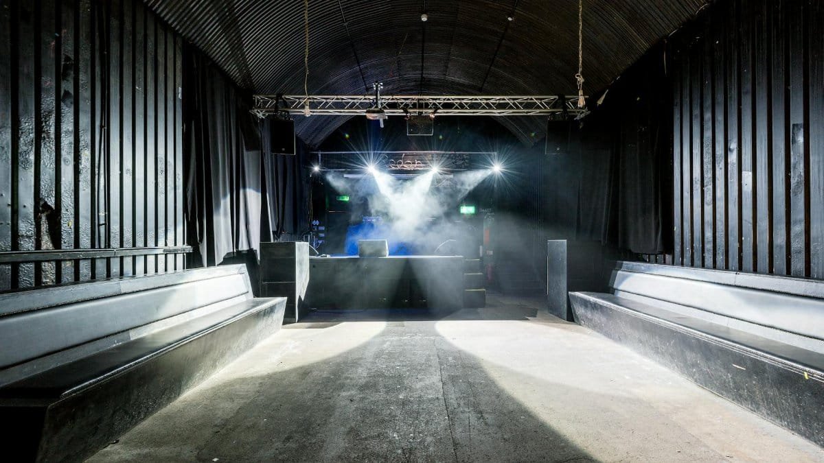 A deserted nightclub featuring stage lighting and seating, highlighting its industrial design.