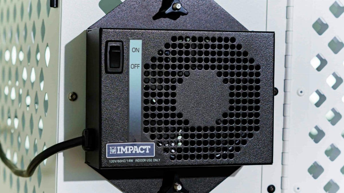 Close-up of an Impact dog crate fan installed on a metal surface, showcasing its design and functionality.