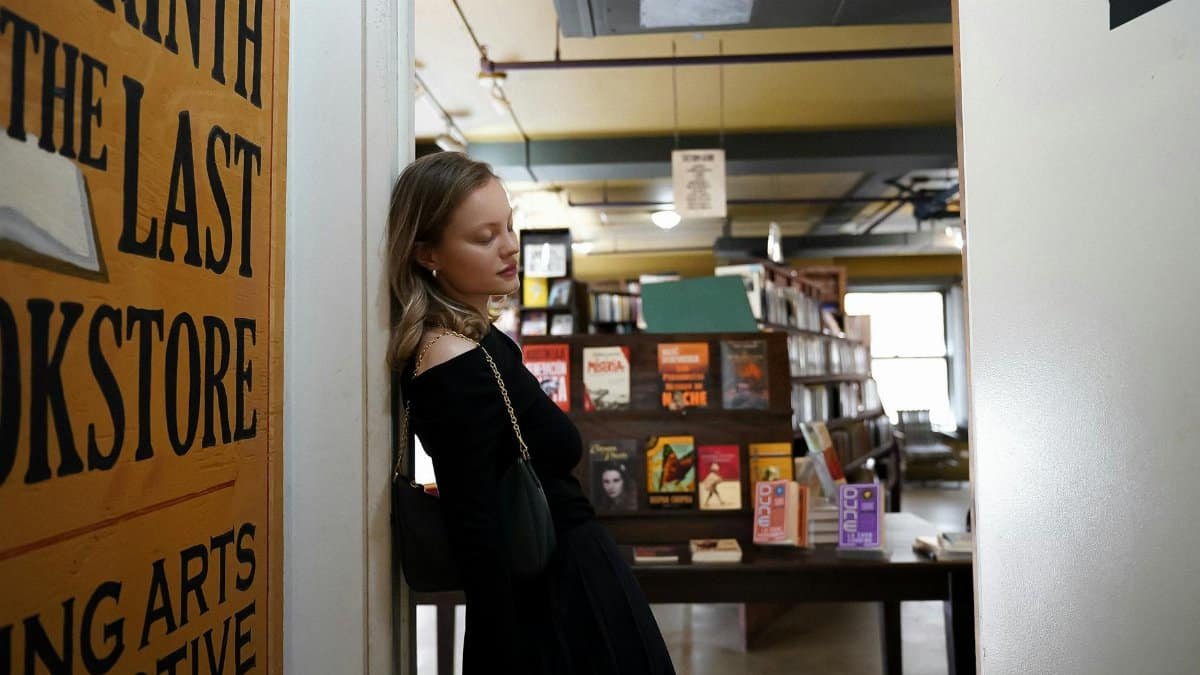 A young woman leaning on a wall inside The Last Bookstore in Los Angeles.