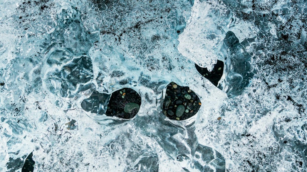 Close-up of ice with embedded rocks, showcasing winter frost patterns.