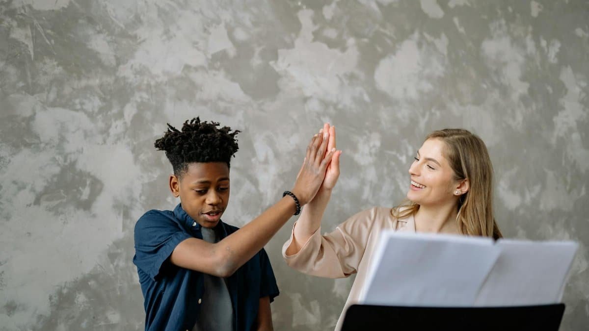 A child and teacher celebrate success with a high five during piano lessons, ensuring a positive learning environment.