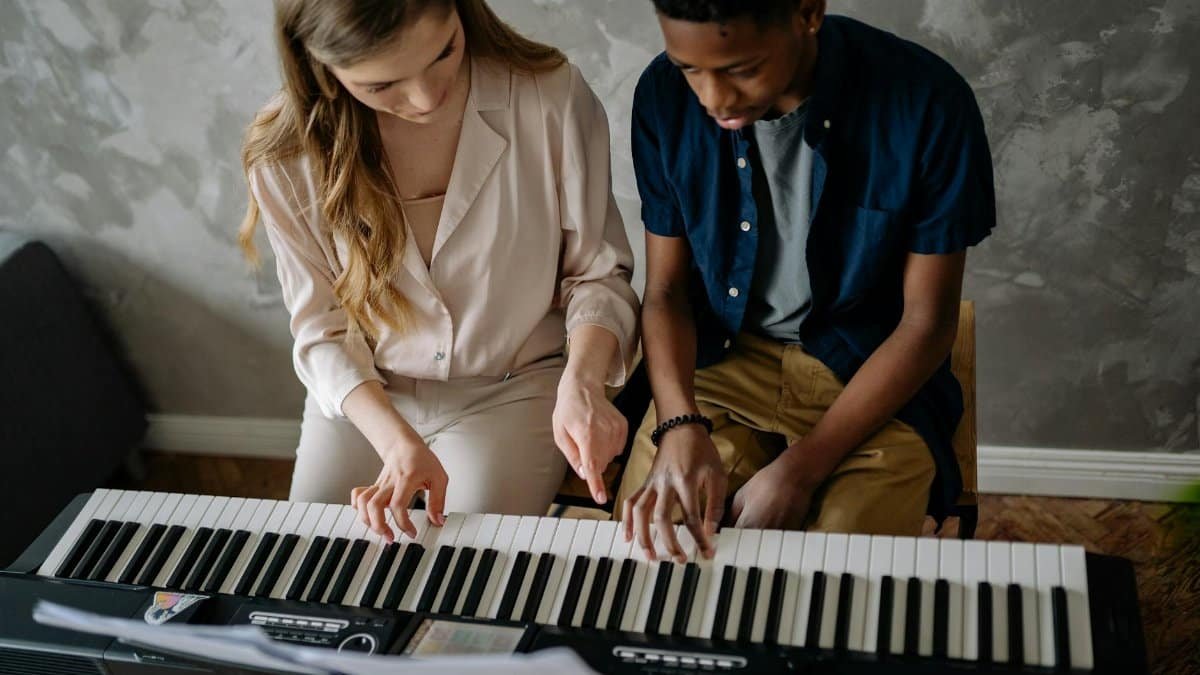 Teenager learning piano with an adult teacher, capturing an intimate musical moment.