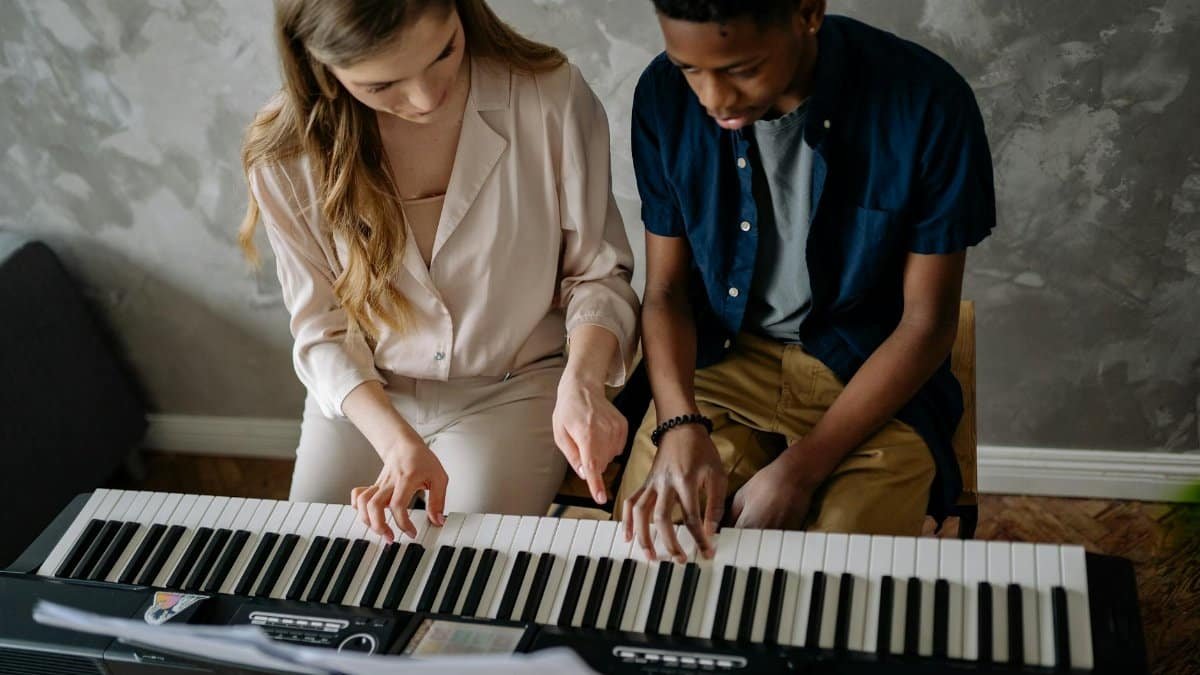 Teenager learning piano with an adult teacher, capturing an intimate musical moment.