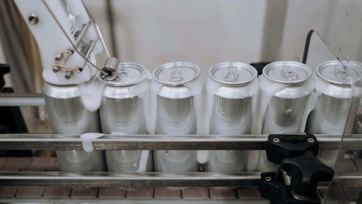 Close-up of aluminum cans on an assembly line in a modern brewery showing automation and machinery at work.