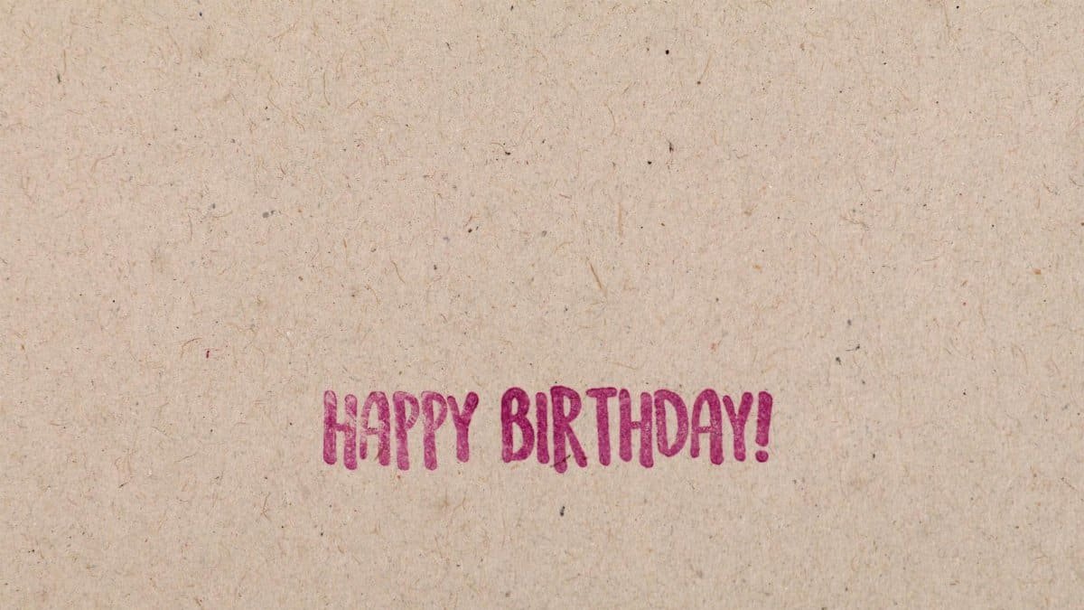 Minimalist 'Happy Birthday' message on a brown textured paper background.