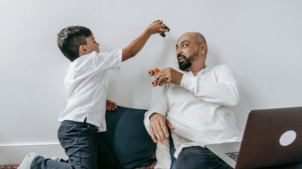 A father and son share a playful moment indoors, enjoying quality bonding time together.