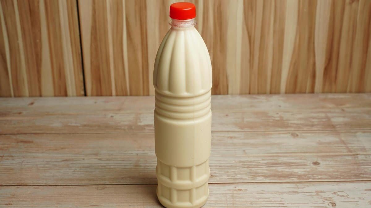 Close-up of a plastic milk bottle with a red cap on a rustic wooden table with copy space.