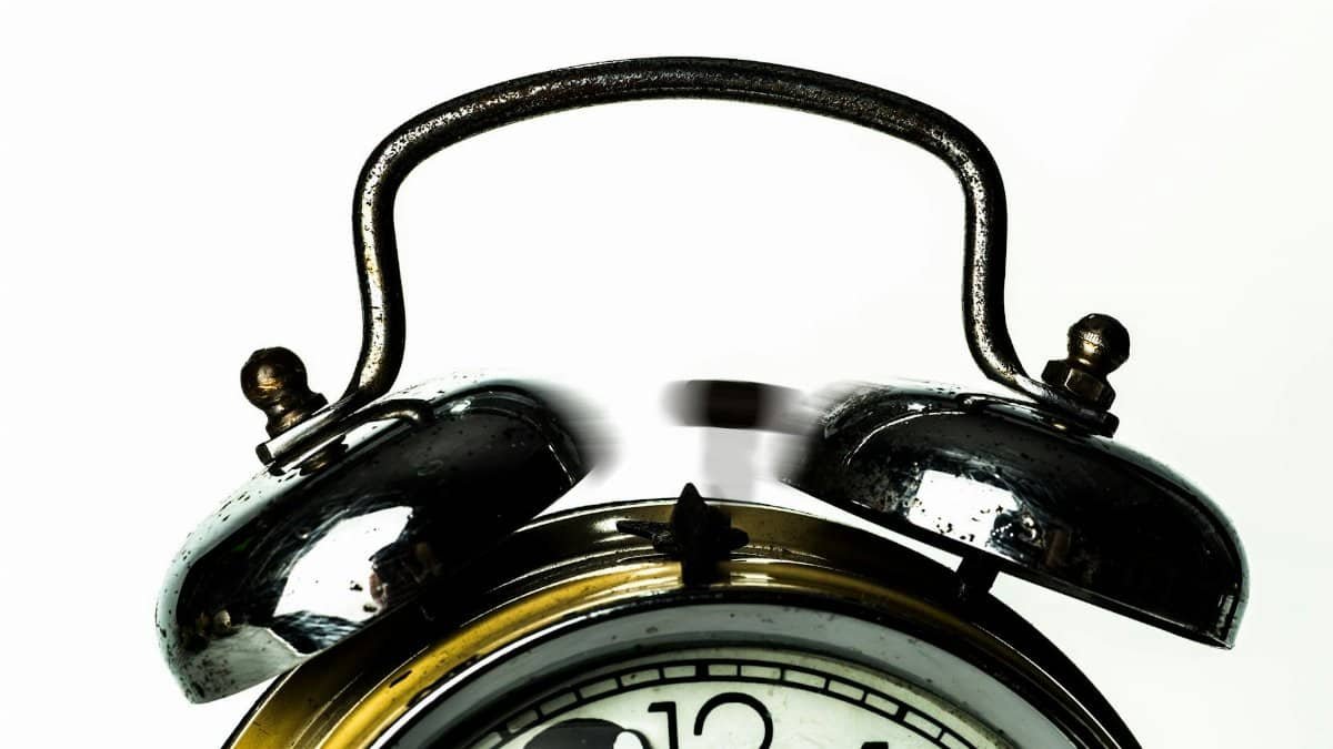 Close-up of a classic vintage alarm clock with ringing bells on a white background.