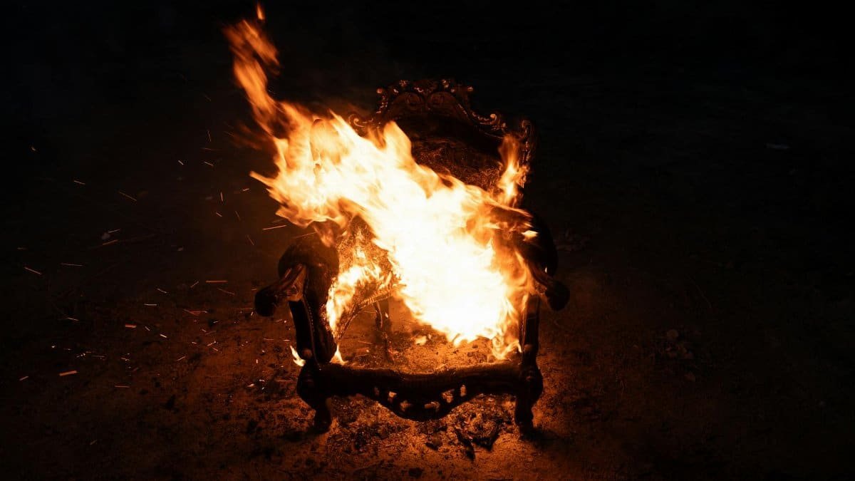 A wooden chair engulfed in flames, creating a dramatic night scene.