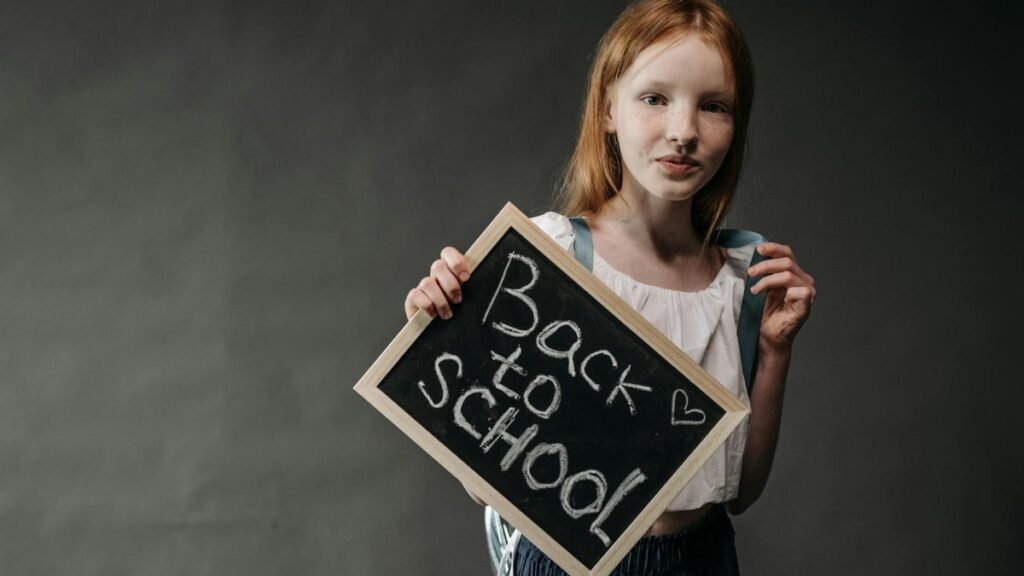 Young girl holding a blackboard with 'Back to School' message, perfect for educational themes.