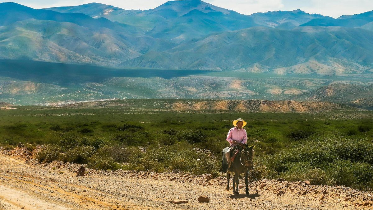 Explore the rugged terrain with a lone rider against a breathtaking mountain backdrop.