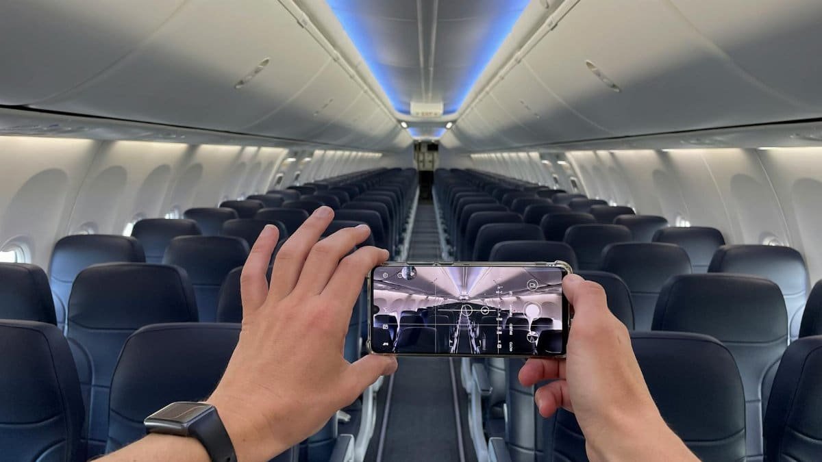 Photo of empty airplane cabin taken with a smartphone, showing rows of seats and aisle.