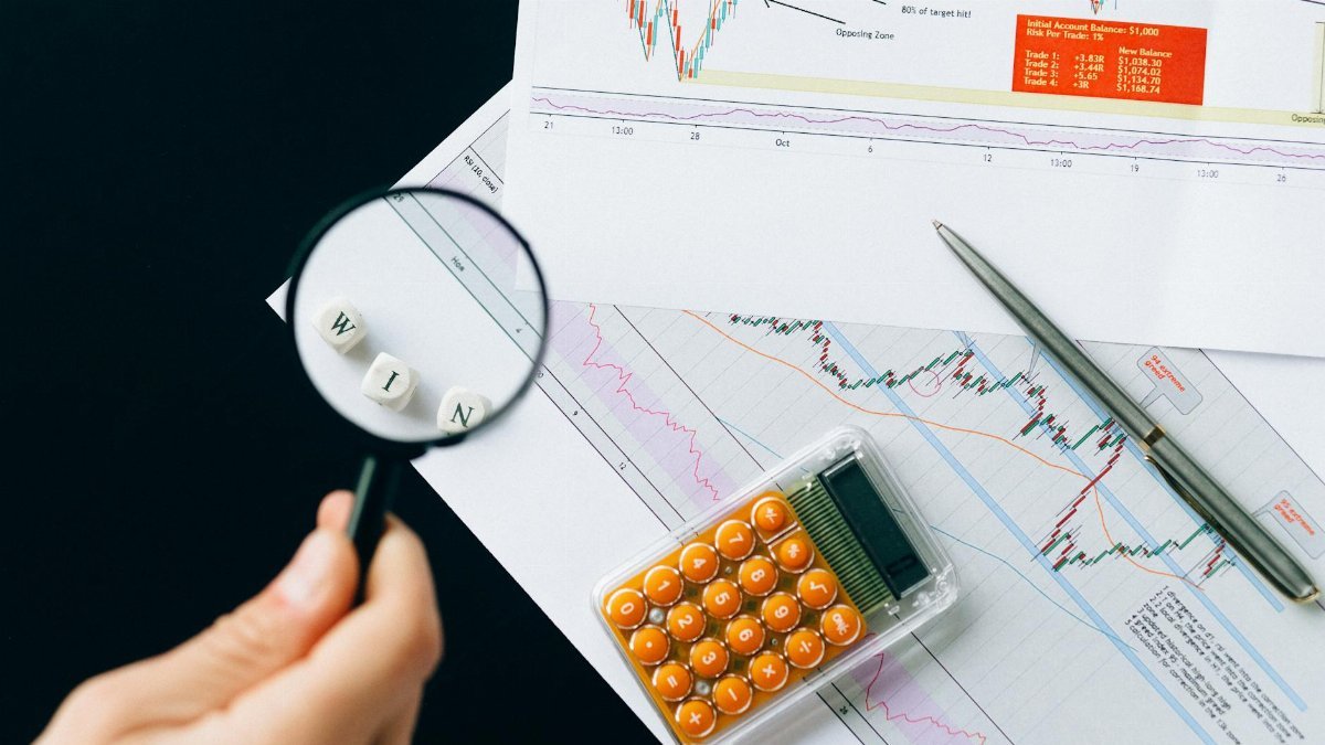 Magnifying glass highlighting the word 'WIN' over financial charts. Enhance your business analysis vision.