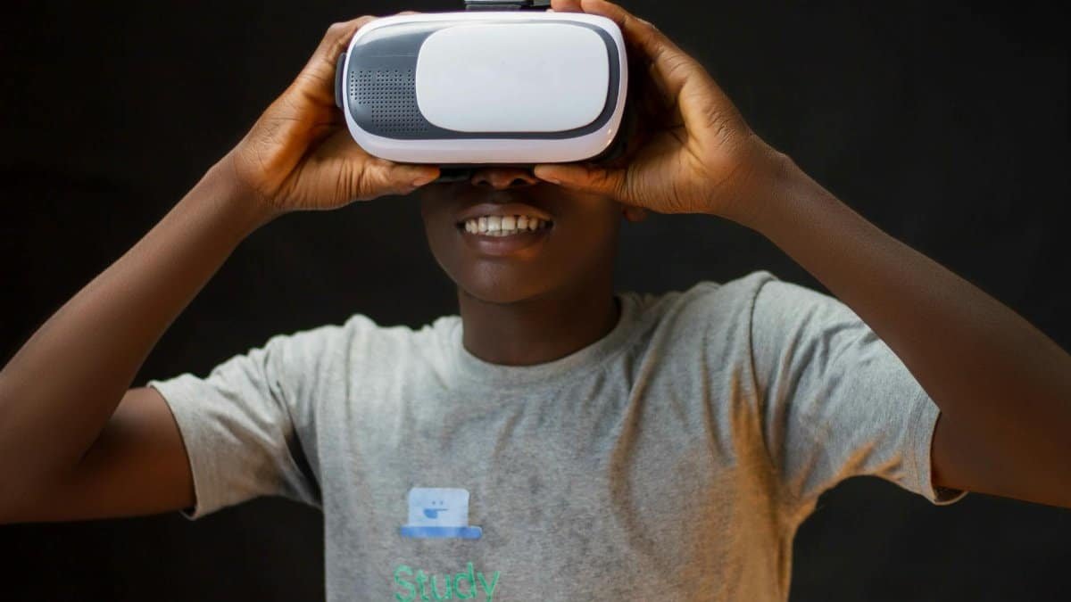 Adult wearing VR headset, experiencing virtual reality with a joyful expression against a dark background.