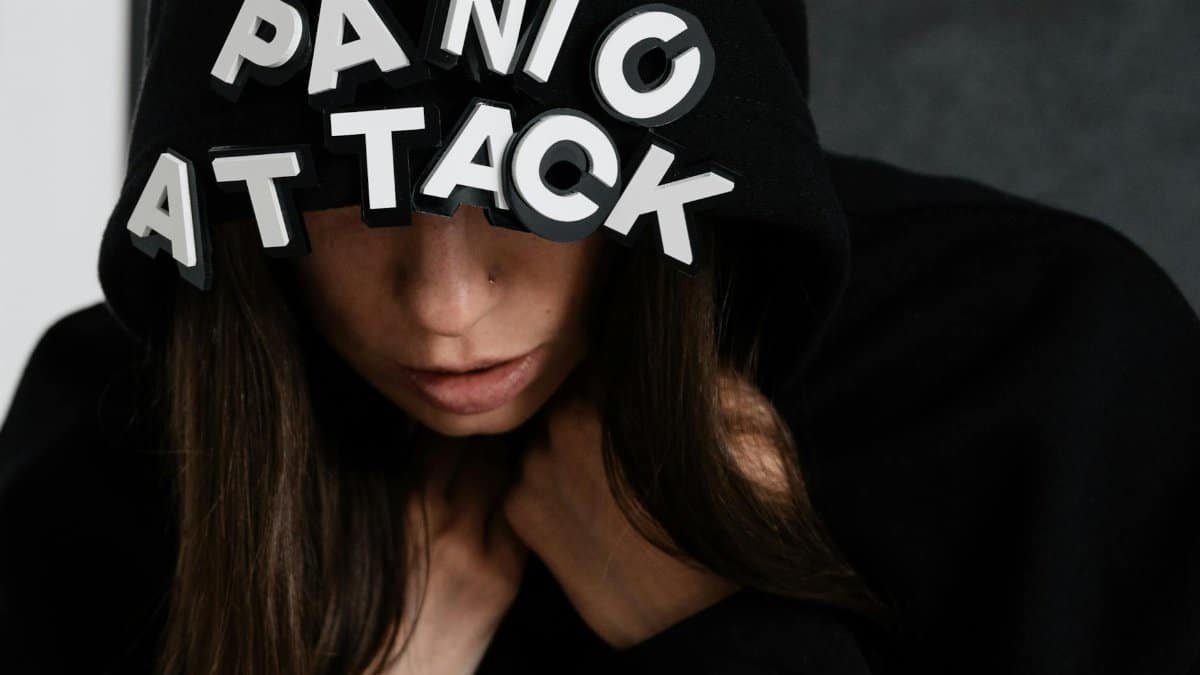 Close-up of a woman in a hoodie with the words 'panic attack', capturing mental health struggles.