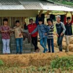 A cheerful group of boys posing near a rural structure in Indonesian farmland.