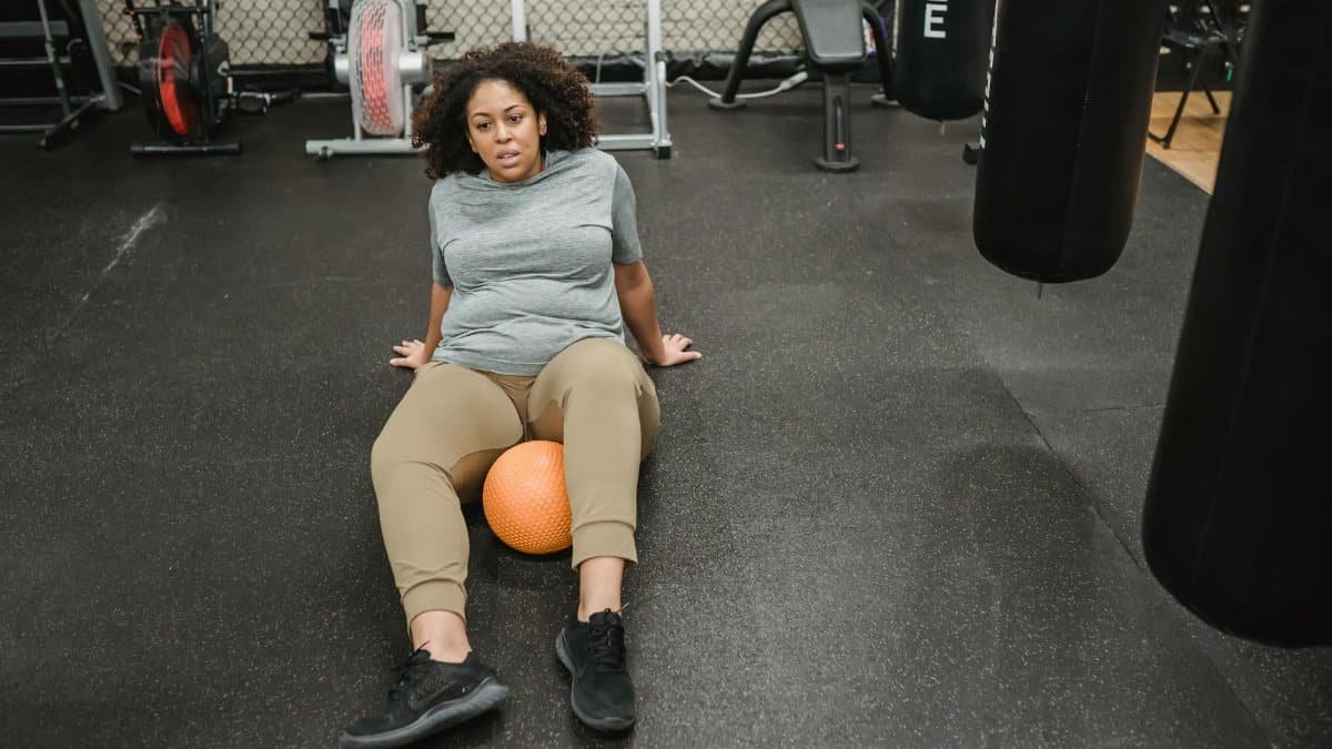 A determined woman working out with a stability ball, enhancing core strength in a gym setting.