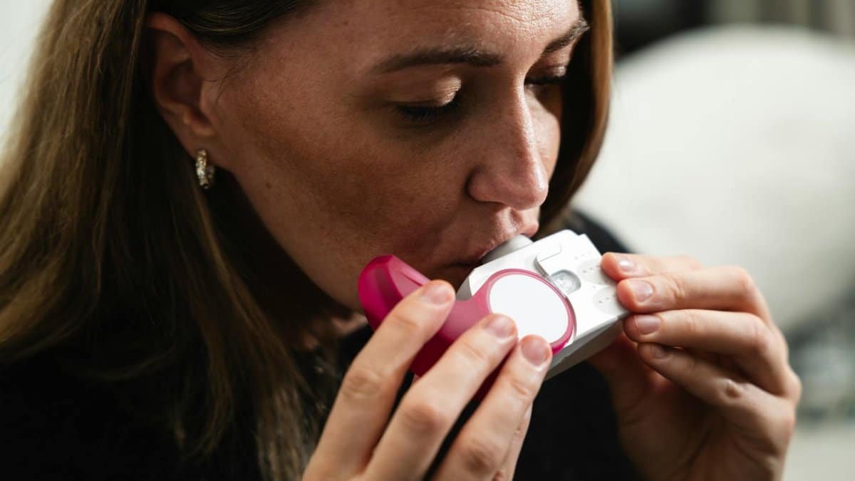Close-up of a woman using an inhaler for respiratory health management.