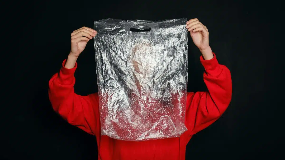 Conceptual image of a person holding a clear plastic bag, symbolizing pollution and recycling themes.