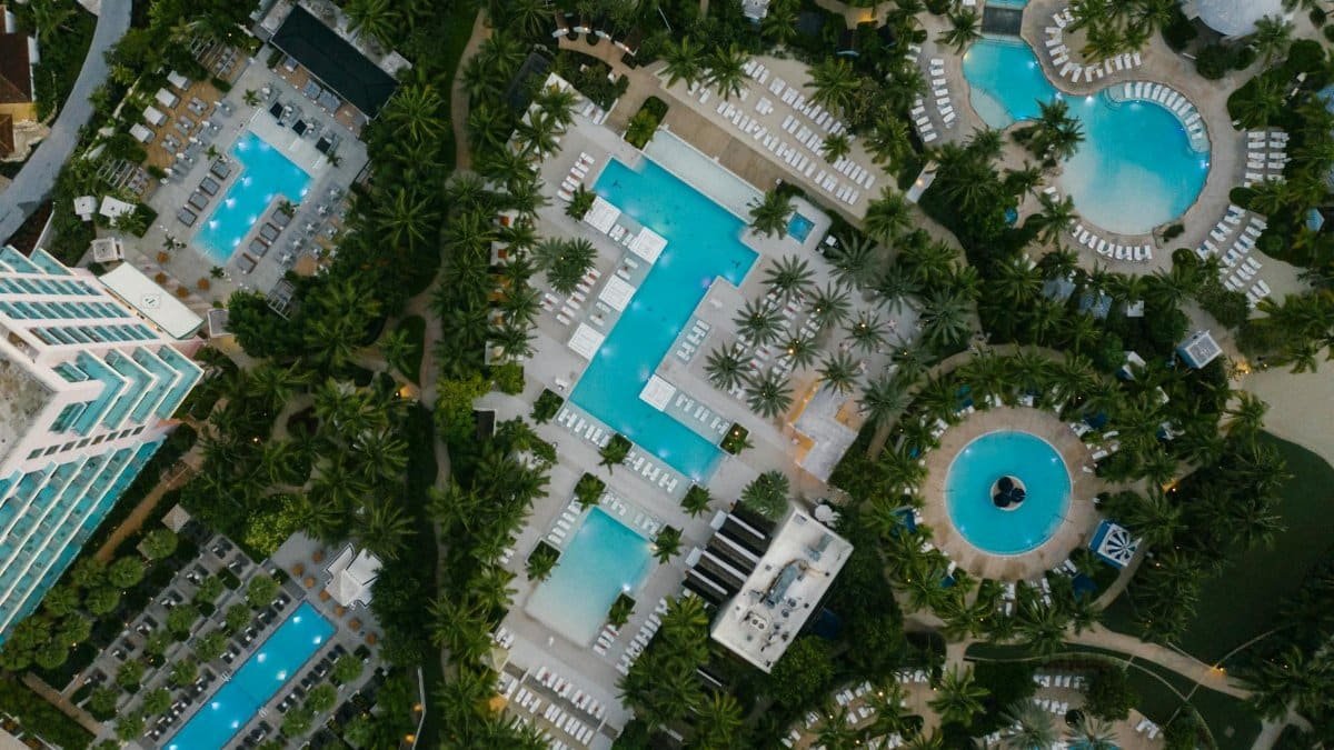 Aerial view of a luxury resort featuring swimming pools, palm trees, and elegant architecture at a tropical destination.