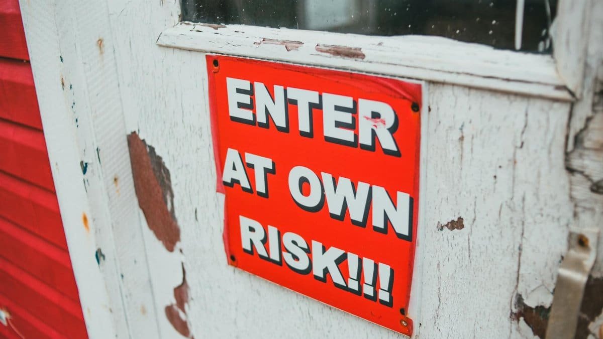 Close-up of a bright red warning sign on a weathered wooden door.