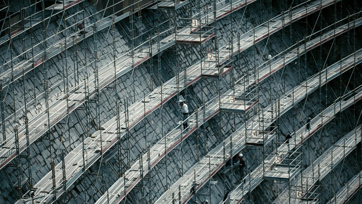 Detailed view of scaffolding on a massive construction site with workers.