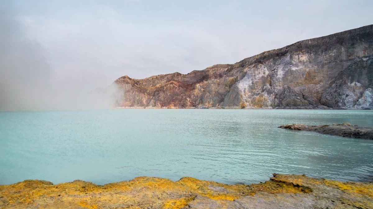 Serene landscape featuring the turquoise waters of Kawah Ijen crater lake, famous for its sulfur mining.