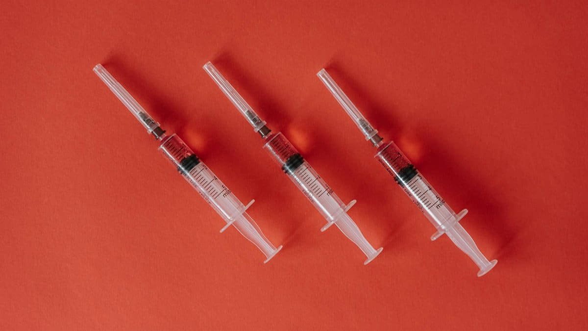 Three syringes arranged on a red surface showcasing medical equipment with copy space.