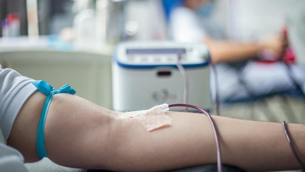 A detailed close-up of an arm during the blood donation process in a medical setting.