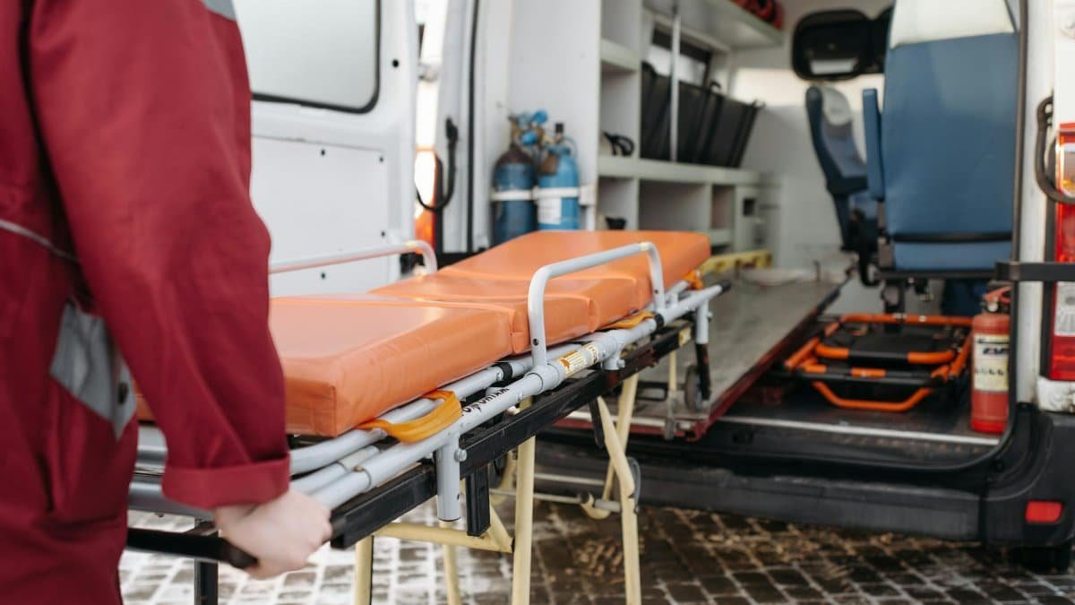 A paramedic loads a stretcher into an ambulance, showcasing emergency medical services in action.