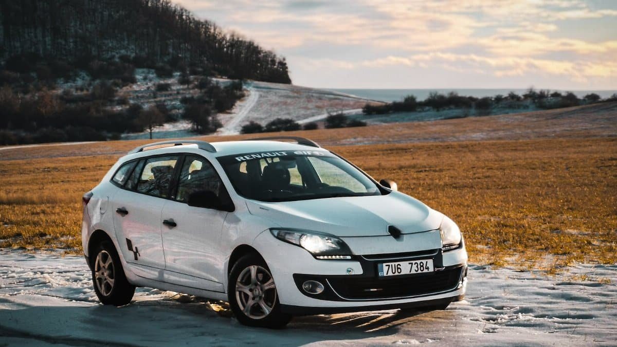 White Renault car parked on a snowy field in Czechia, capturing a serene winter landscape.