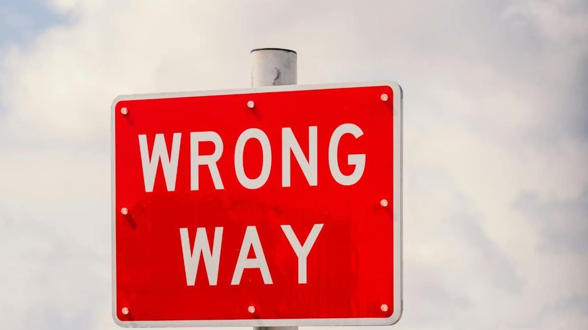 Clear image of a bright red 'Wrong Way' traffic sign against a cloudy sky in Miami, Florida.