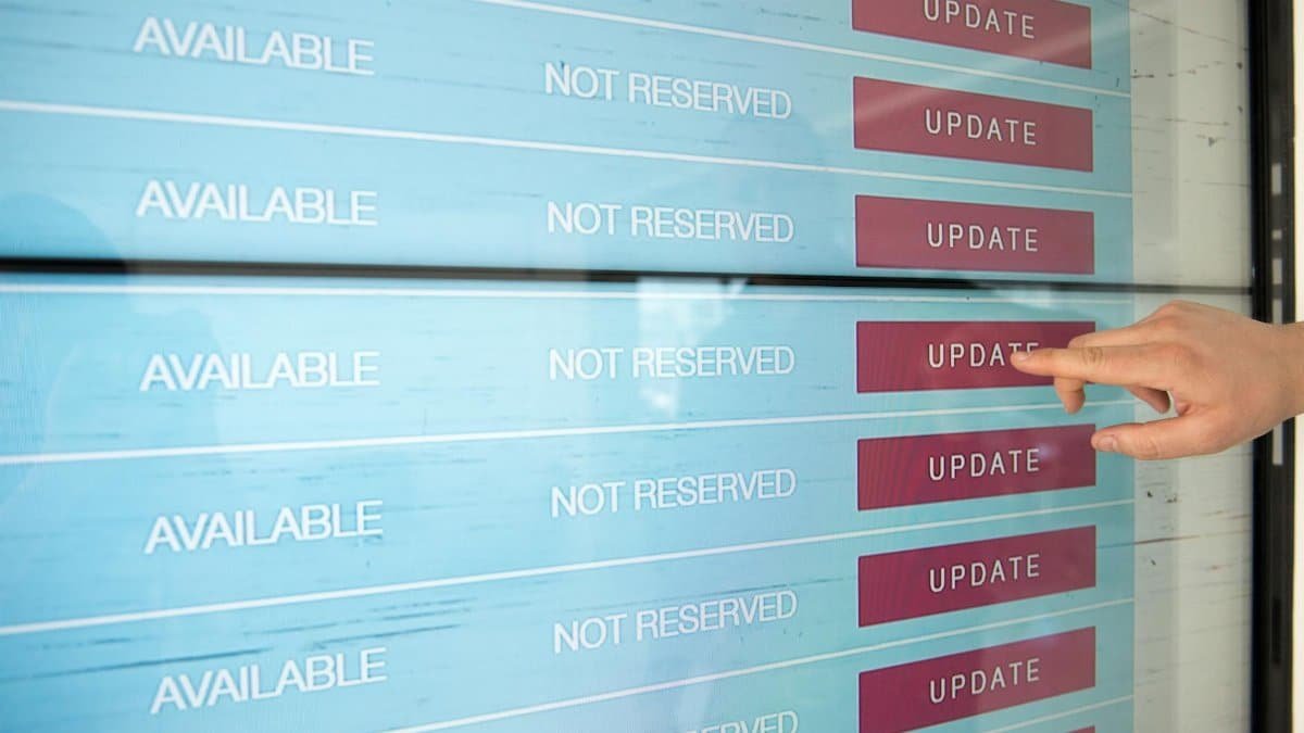 A hand interacts with a digital touchscreen interface showing availability and update options.