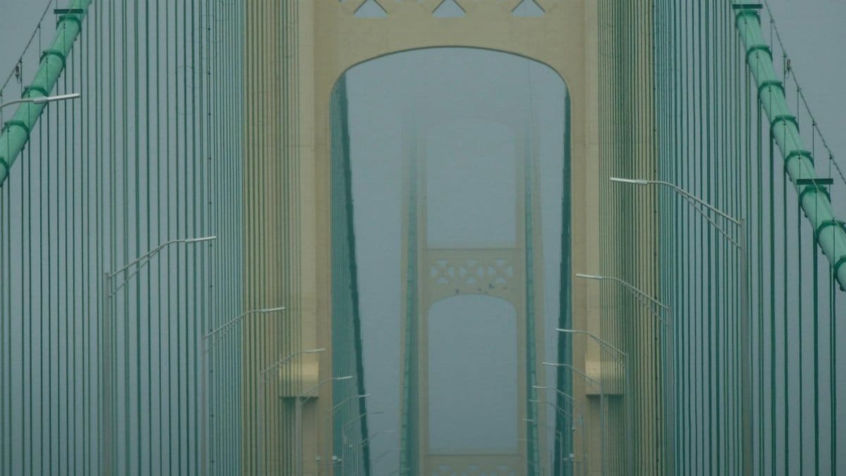 A misty view of the iconic Mackinac Bridge in Michigan shrouded in fog.