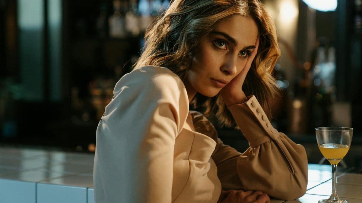 Elegant woman sitting at a bar counter with a cocktail, lost in thought.