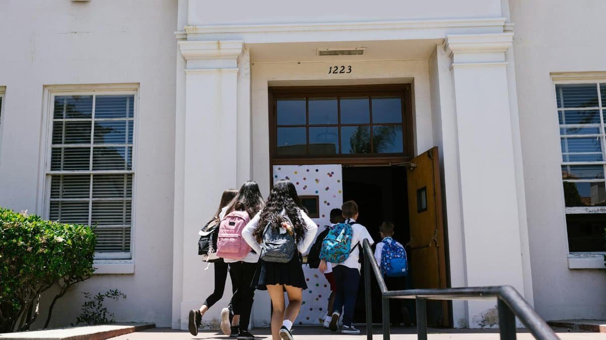 Group of students with backpacks entering a school building. Perfect for back-to-school themes.