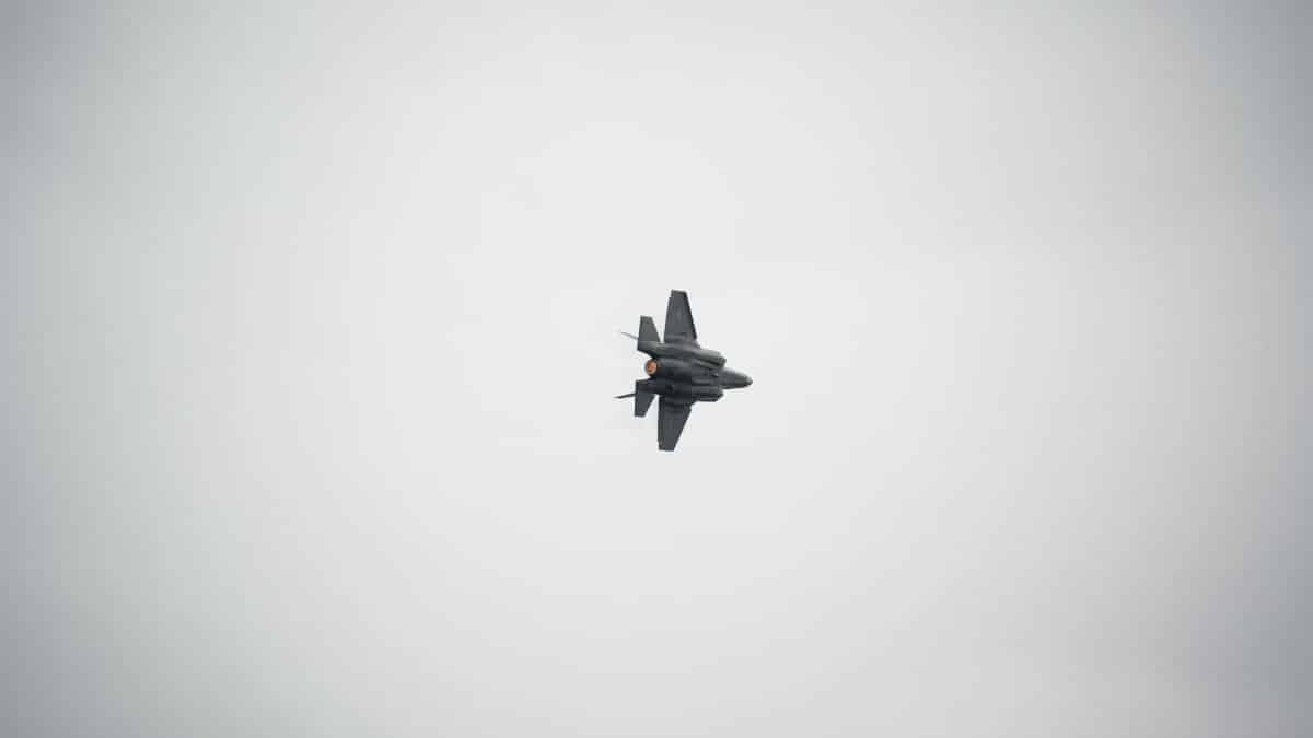 A dynamic fighter jet flies against a cloudy sky, showcasing military aviation power.