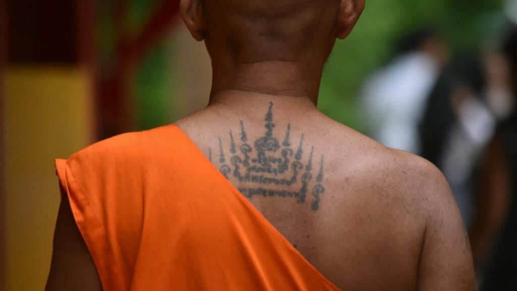 Thoughtful moment of a tattooed monk amidst spirituality in Bangkok temple.