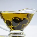 High-resolution image of a glass cup filled with olive oil and olives, ideal for culinary themes.