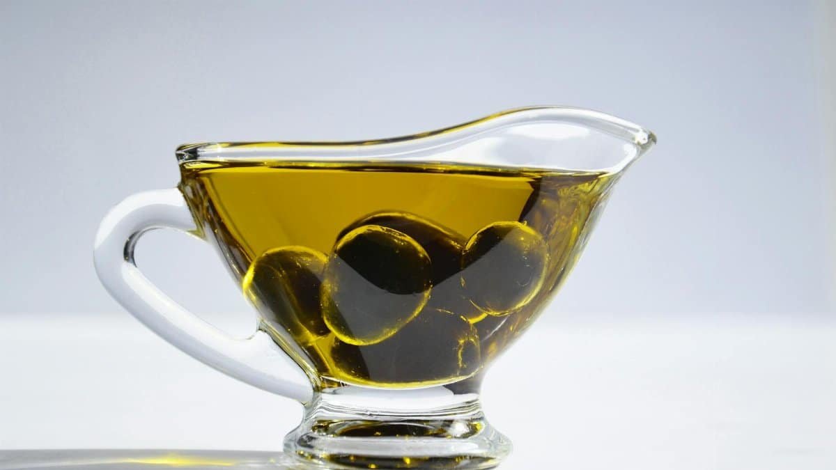 High-resolution image of a glass cup filled with olive oil and olives, ideal for culinary themes.