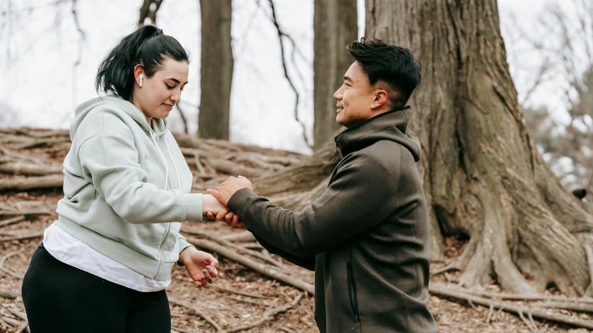 A personal trainer assists a client in a park during a workout session, promoting fitness and motivation.
