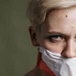 A defiant woman with taped mouth symbolizes silenced voices and human rights.