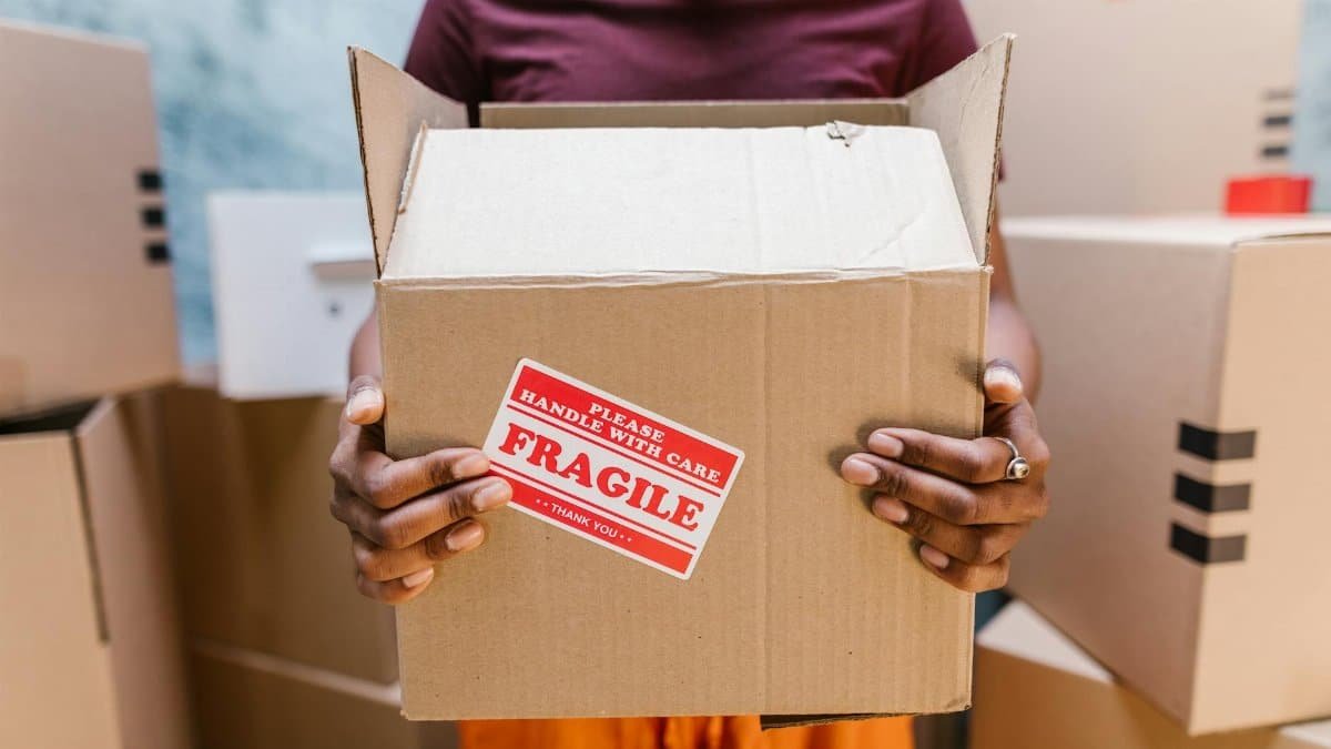 A person holding a cardboard box labeled 'Fragile' during a moving process indoors.