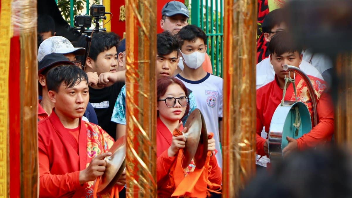 Musicians in bright costumes playing traditional instruments at an Asian street festival.