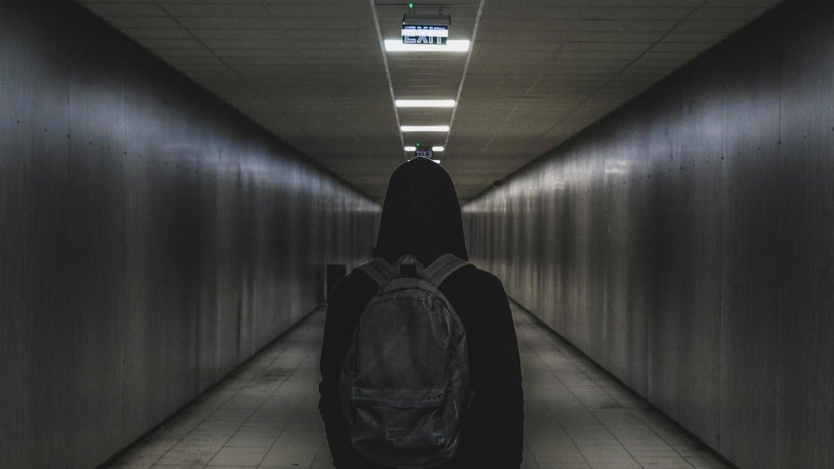 A person with a backpack walks through a dimly lit tunnel, conveying mystery and solitude.