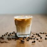 Refreshing iced latte with coffee beans on a wooden table surface.