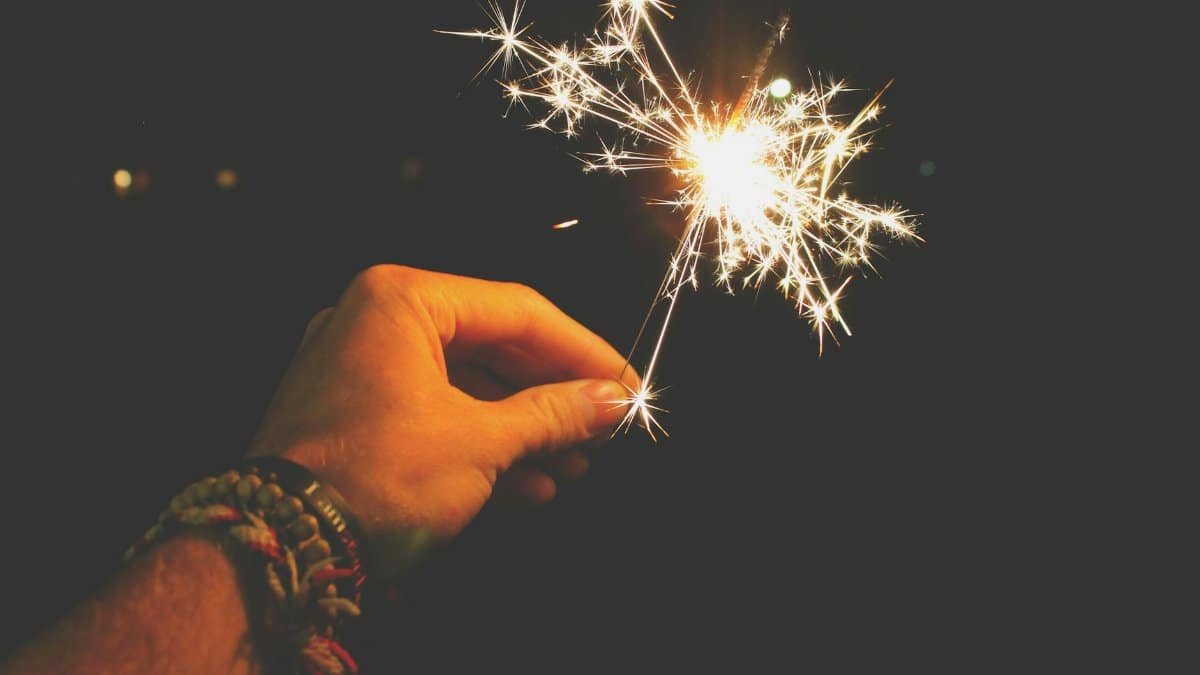 A hand holding a sparkling sparkler in the dark, perfect for festive celebrations.