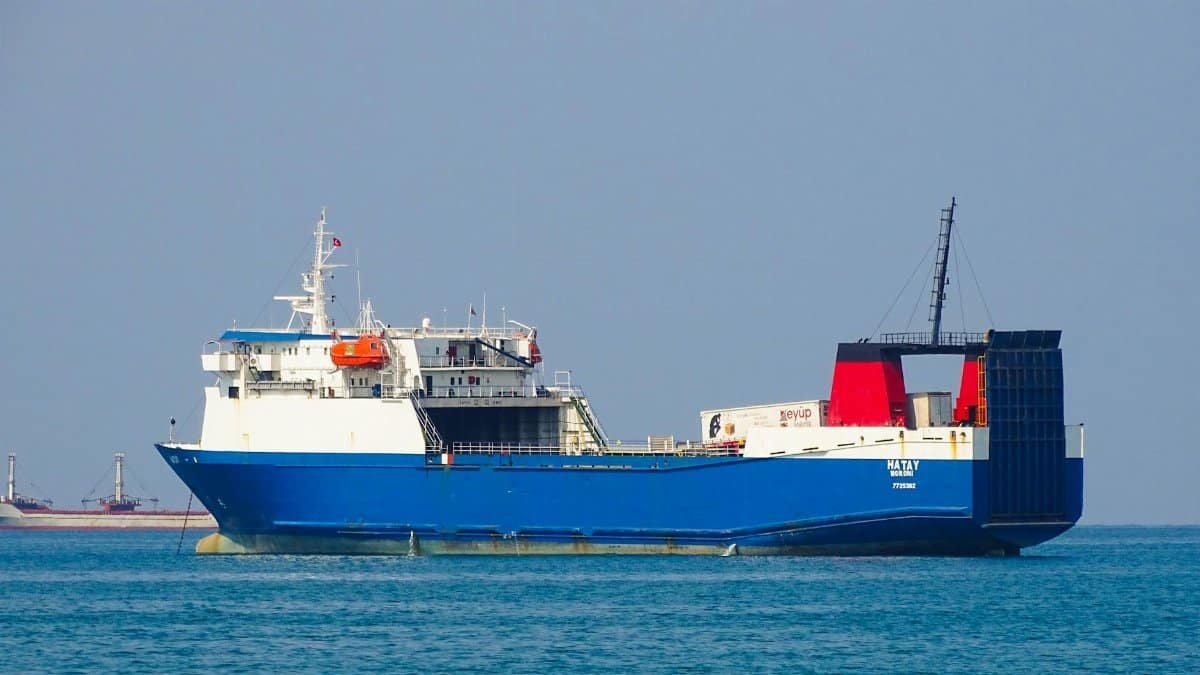 A large blue cargo ship navigating the calm ocean waters under a clear sky.
