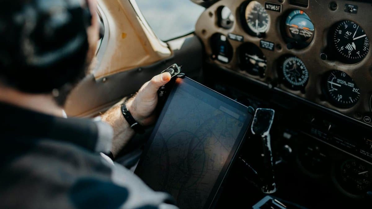 Pilot using tablet for navigation inside an airplane cockpit, showcasing aviation technology.